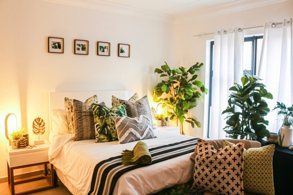 a clean and tidy bedroom with plants and lots of pillows 