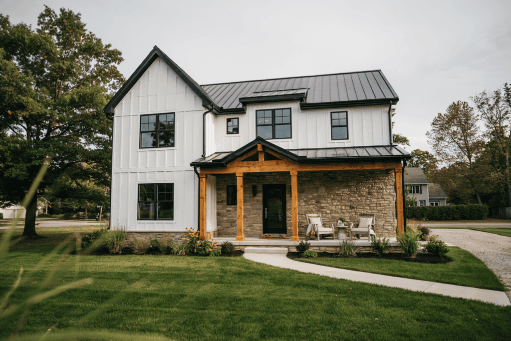 modern farmhouse exterior with chairs on the front porch, and a manicured lawn 