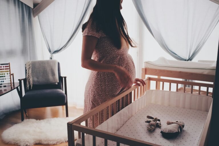 nursery bedroom with pregnant woman standing over crib