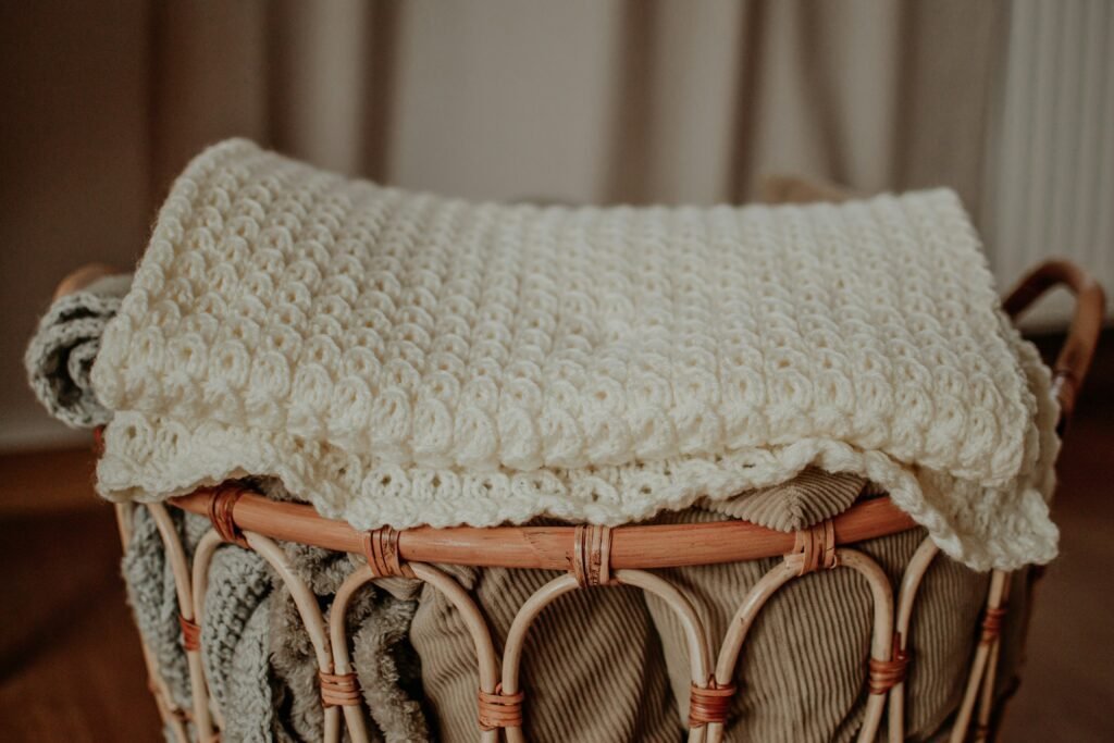 a woven basket with a folded chunky blanket on top of it 