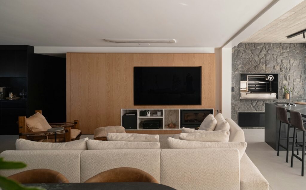 How to Create a Warm Minimalist Home: The Ultimate Design Guide warm minimalist living room with large television on wall and a stone wall to the right
