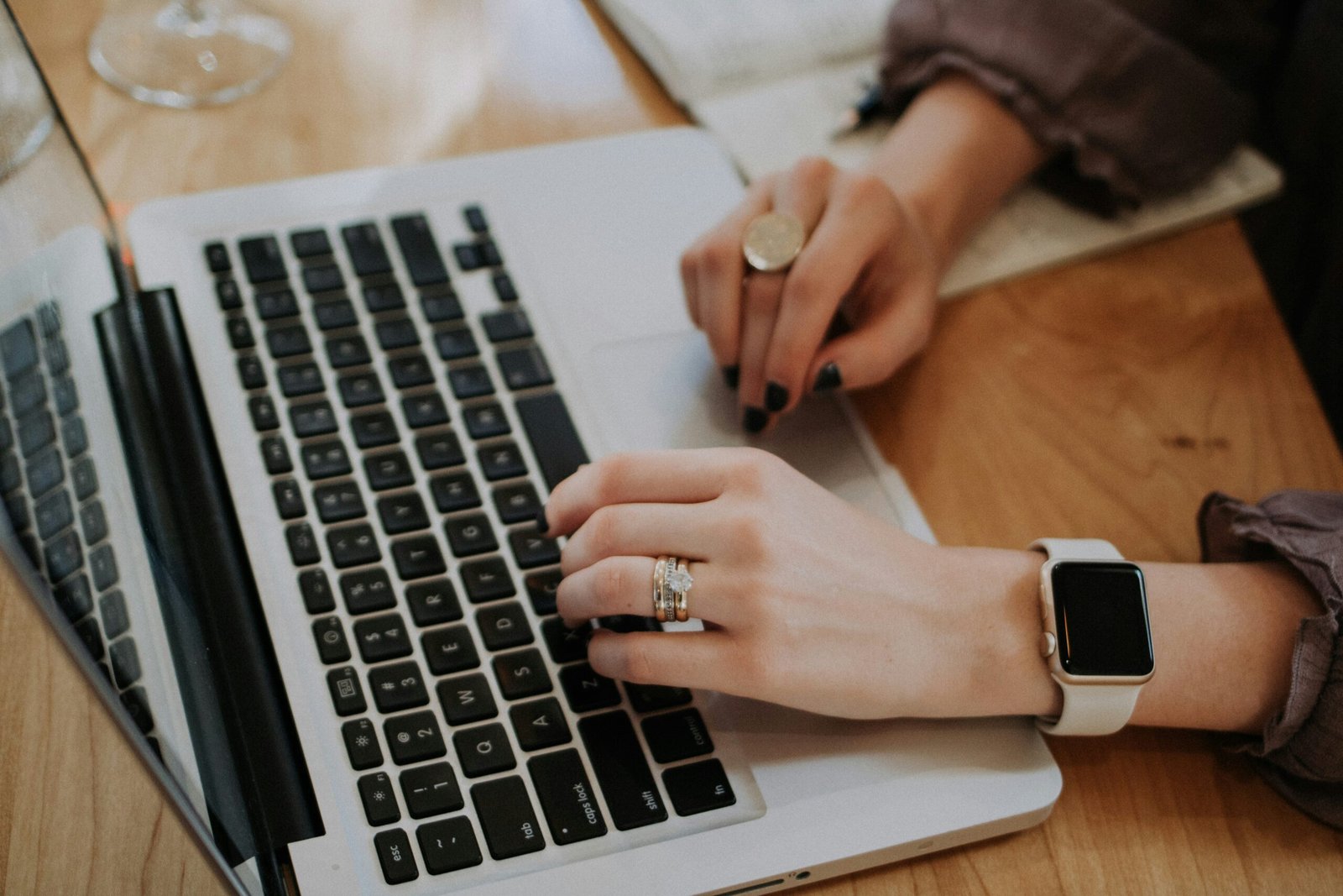 a women's hands typing on a laptop
